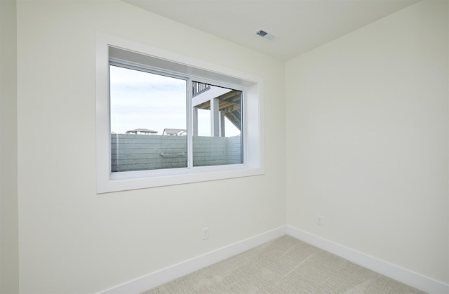 empty room with visible vents, light carpet, and baseboards