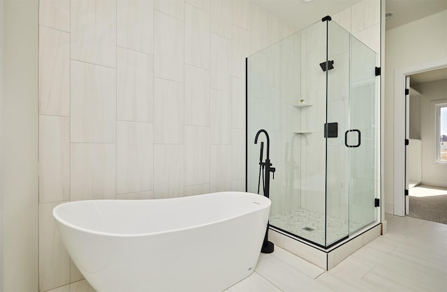 full bathroom with tile walls, a freestanding bath, and a shower stall