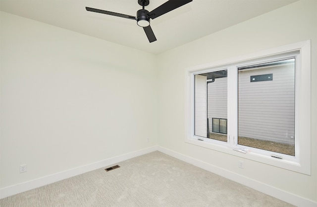 spare room featuring light carpet, a ceiling fan, visible vents, and baseboards