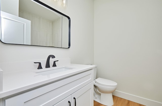 bathroom featuring baseboards, vanity, toilet, and wood finished floors