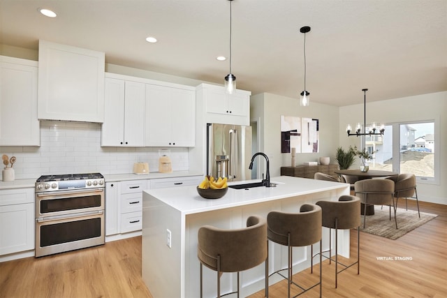 kitchen with appliances with stainless steel finishes, a sink, light wood-style flooring, and tasteful backsplash