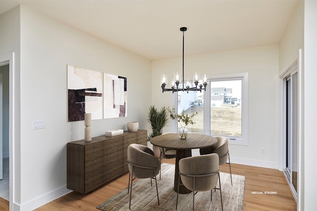 dining space featuring a chandelier, light wood-style flooring, and baseboards