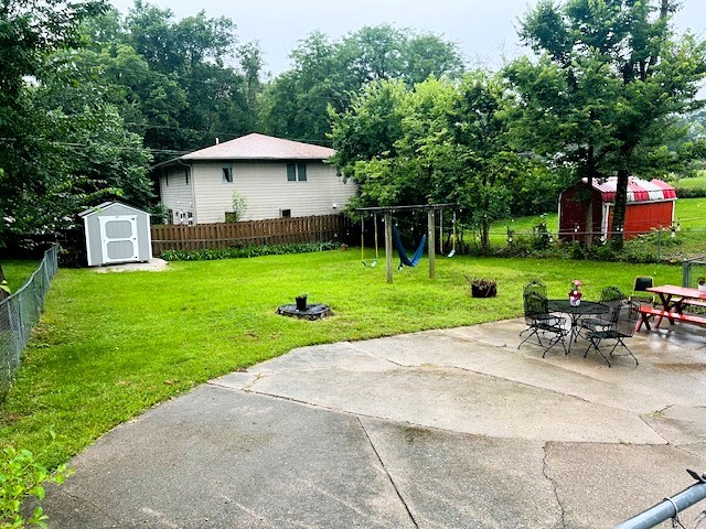 view of yard featuring a playground, a patio, and a shed