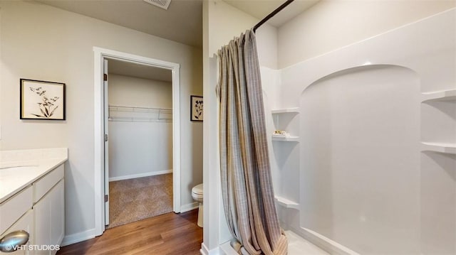 bathroom featuring walk in shower, vanity, toilet, and wood-type flooring