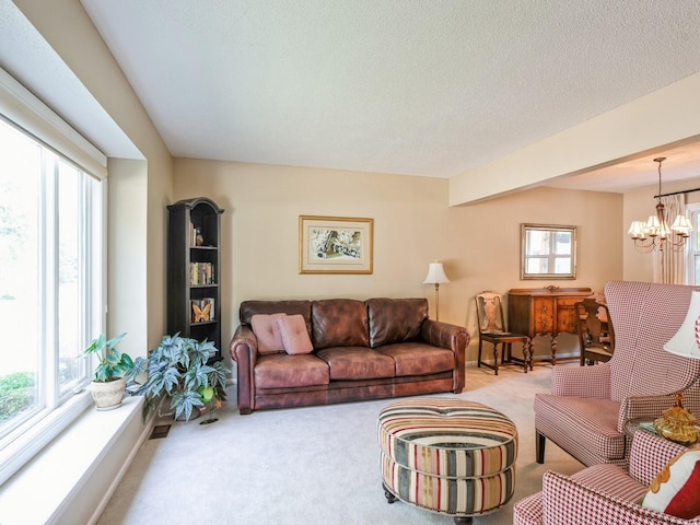 living room with an inviting chandelier, carpet, baseboards, and a textured ceiling