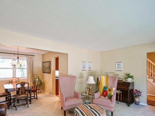 sitting room featuring baseboards, stairs, a textured ceiling, light colored carpet, and a chandelier