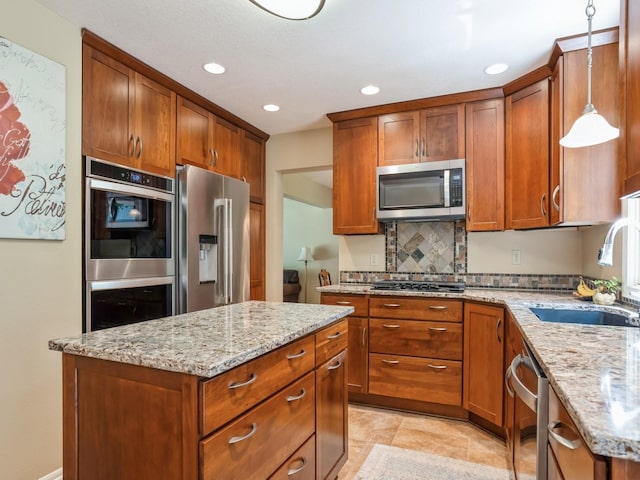 kitchen featuring a sink, light stone counters, brown cabinets, and stainless steel appliances