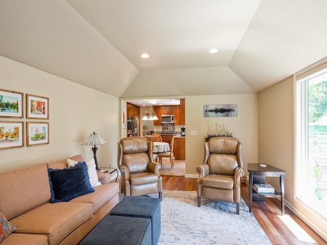 living room with baseboards, an inviting chandelier, recessed lighting, vaulted ceiling, and light wood-type flooring