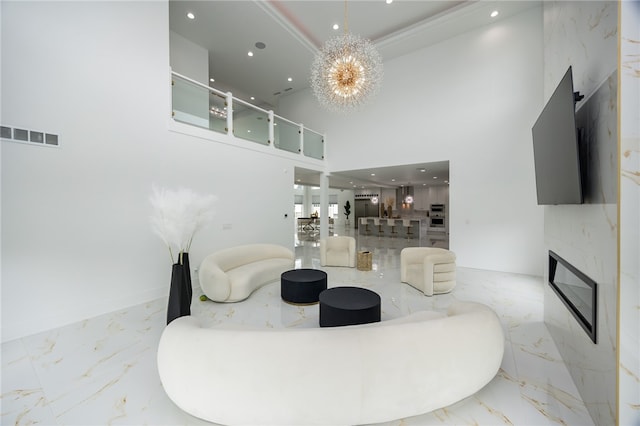 living room featuring a towering ceiling, a fireplace, an inviting chandelier, and light tile patterned floors