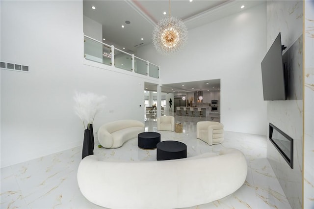 living area featuring a glass covered fireplace, marble finish floor, an inviting chandelier, and recessed lighting