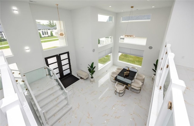 foyer featuring plenty of natural light, marble finish floor, a towering ceiling, and stairway