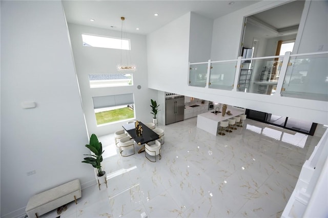 foyer entrance featuring marble finish floor, baseboards, a notable chandelier, and recessed lighting