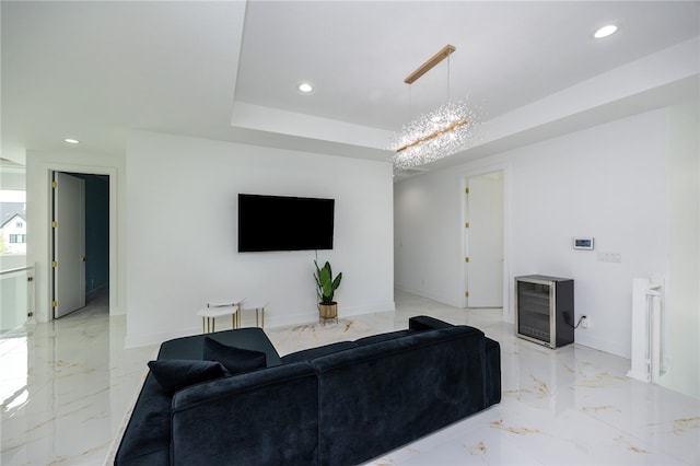 living room featuring a raised ceiling, wine cooler, light tile patterned flooring, and an inviting chandelier