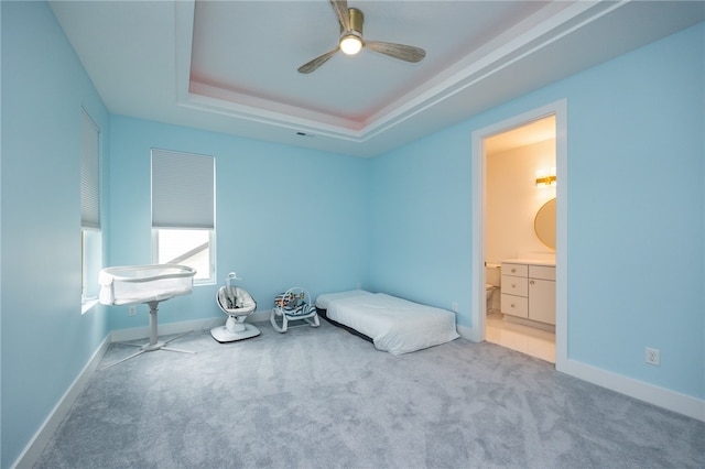 unfurnished bedroom with ceiling fan, a raised ceiling, carpet, and ensuite bathroom