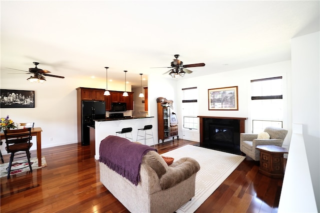 living room featuring ceiling fan and dark wood-type flooring