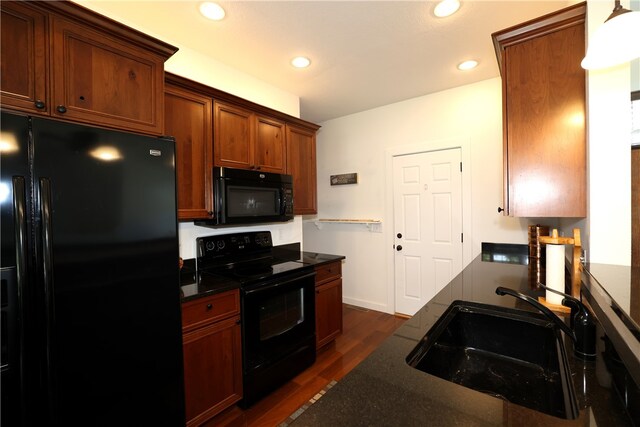 kitchen with sink, dark wood-type flooring, decorative light fixtures, and black appliances