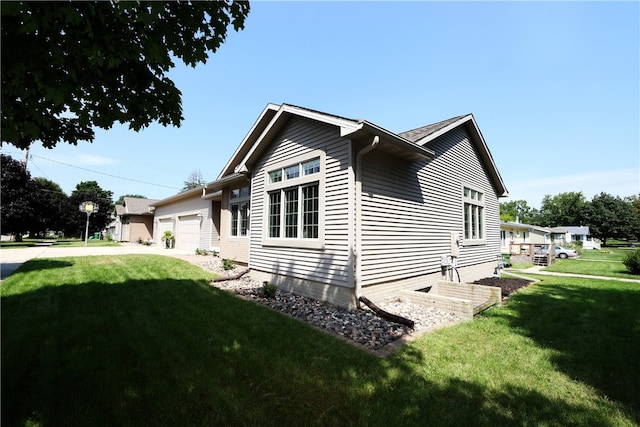 view of side of property featuring a garage and a lawn