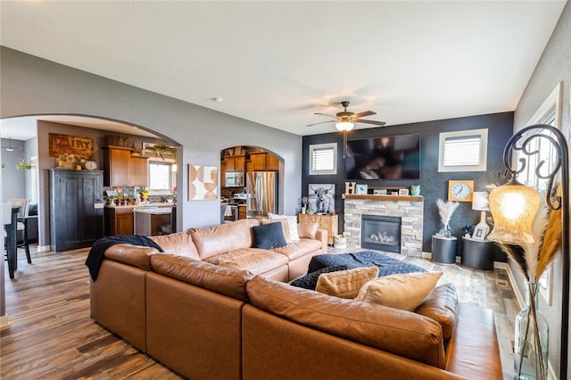 living room featuring ceiling fan, wood-type flooring, and a fireplace