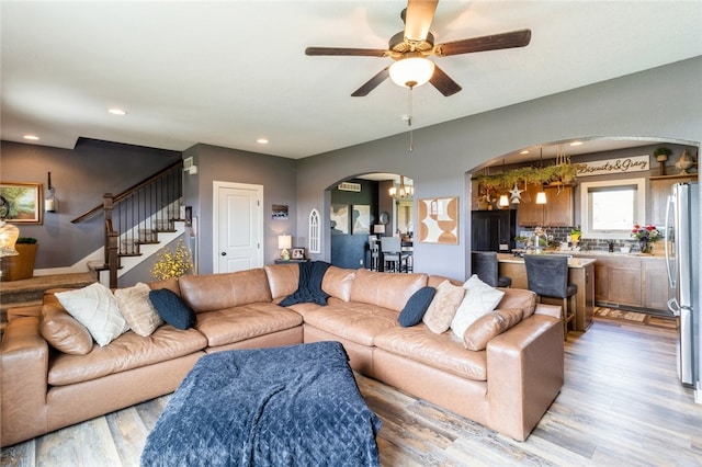 living room with light hardwood / wood-style floors and ceiling fan with notable chandelier