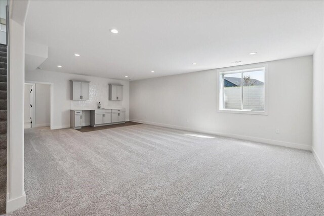 unfurnished living room with sink and light carpet