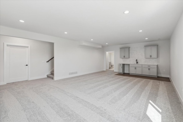 unfurnished living room with light carpet and sink