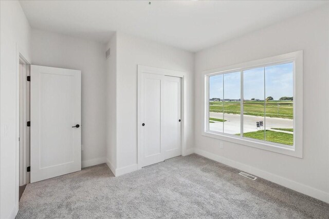 unfurnished bedroom with light colored carpet and a closet