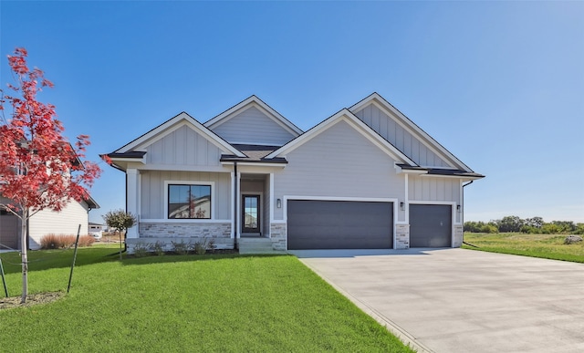 craftsman-style house featuring board and batten siding, a garage, stone siding, and a front lawn