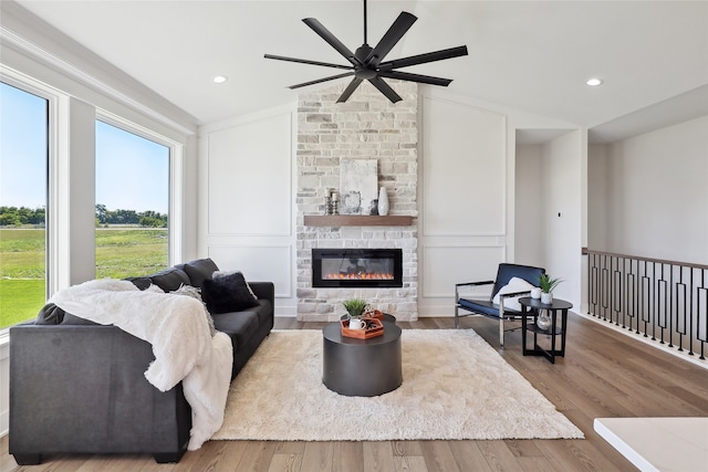 living room with ceiling fan, hardwood / wood-style floors, and a stone fireplace