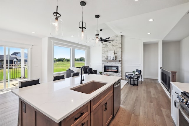 kitchen featuring light hardwood / wood-style floors, sink, lofted ceiling, a fireplace, and stainless steel appliances