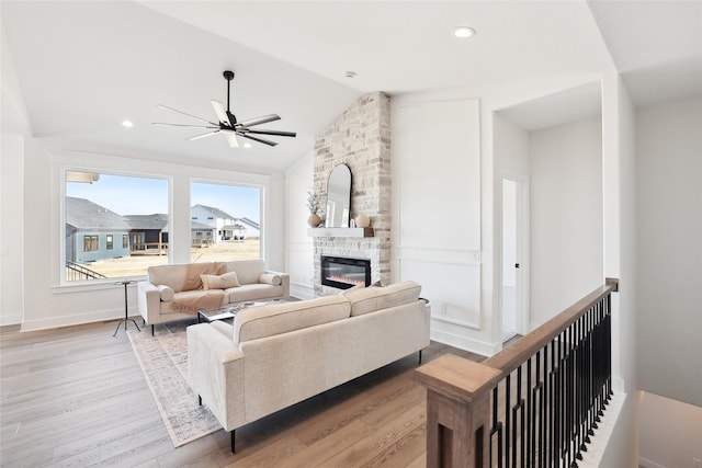 living room featuring baseboards, vaulted ceiling, light wood-style floors, a fireplace, and recessed lighting