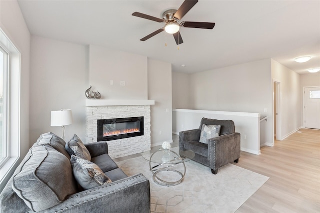 living room with ceiling fan, a fireplace, a wealth of natural light, and light hardwood / wood-style flooring