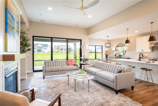 living room featuring ceiling fan, sink, and wood-type flooring