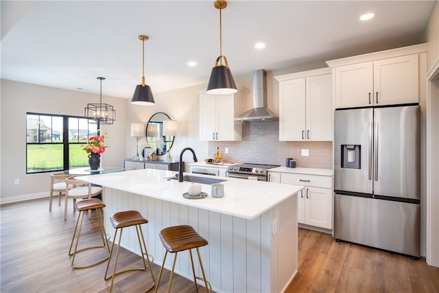 kitchen with sink, light wood-type flooring, wall chimney exhaust hood, stainless steel appliances, and white cabinets