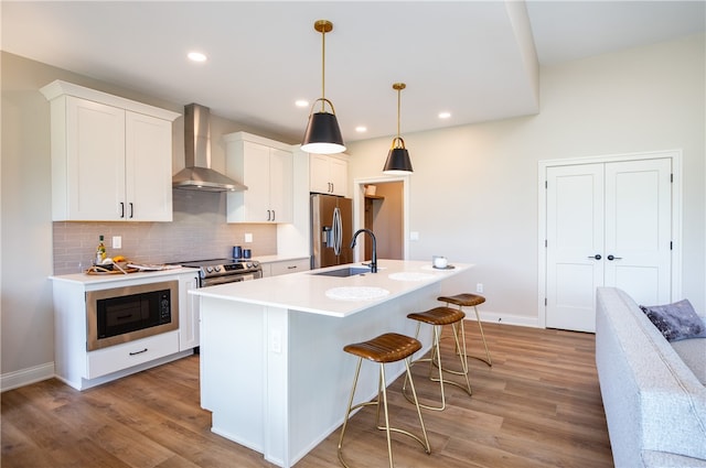 kitchen featuring wall chimney range hood, sink, light hardwood / wood-style floors, and stainless steel appliances