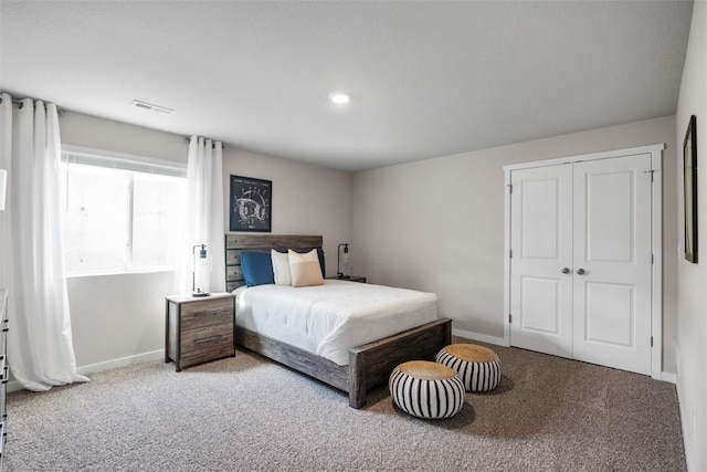 carpeted bedroom with a closet, visible vents, and baseboards