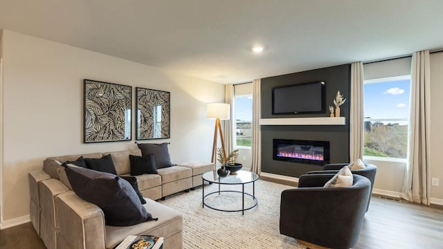 living room featuring a large fireplace, wood finished floors, visible vents, and baseboards