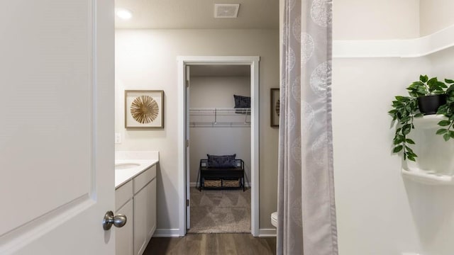 full bathroom with toilet, wood finished floors, visible vents, vanity, and baseboards