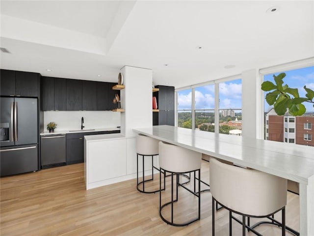 kitchen featuring sink, a breakfast bar area, kitchen peninsula, stainless steel appliances, and light hardwood / wood-style floors