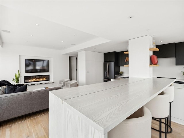 kitchen featuring refrigerator with ice dispenser, light hardwood / wood-style floors, and a kitchen breakfast bar