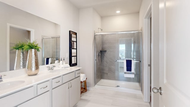 full bathroom featuring a sink, a stall shower, and double vanity