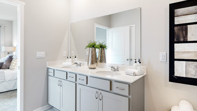 bathroom featuring double vanity, connected bathroom, baseboards, and a sink