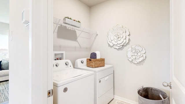 clothes washing area with laundry area, washing machine and dryer, and baseboards