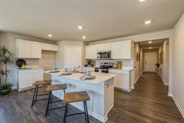 kitchen featuring white cabinetry, a kitchen island with sink, stainless steel appliances, and dark hardwood / wood-style floors