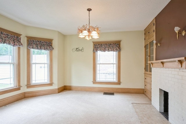 interior space with a wealth of natural light, a fireplace, carpet floors, and a notable chandelier