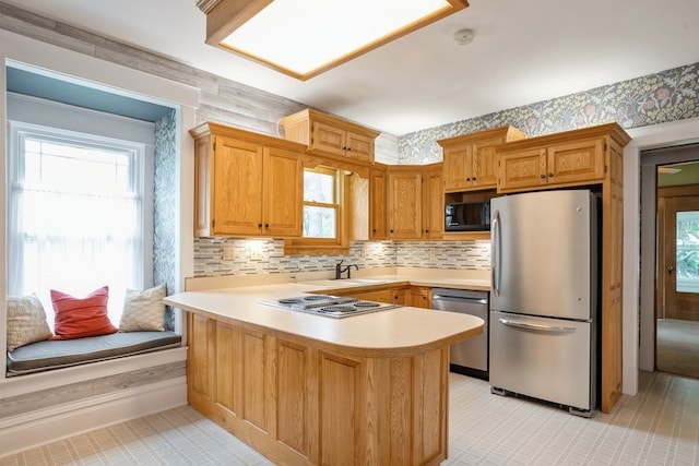 kitchen with kitchen peninsula, decorative backsplash, stainless steel appliances, and sink