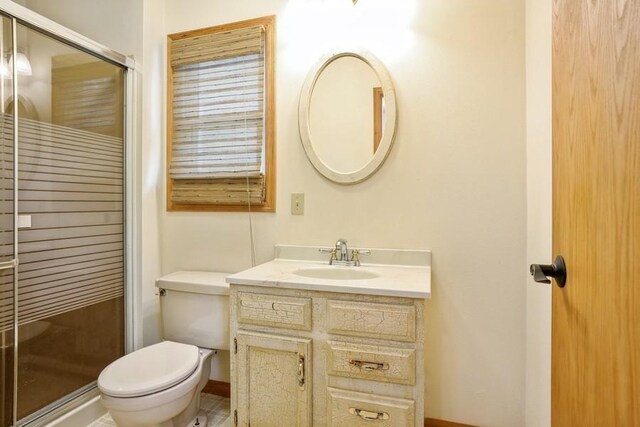 bathroom featuring vanity, toilet, and an enclosed shower