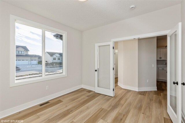 unfurnished bedroom featuring light hardwood / wood-style floors, a closet, and multiple windows