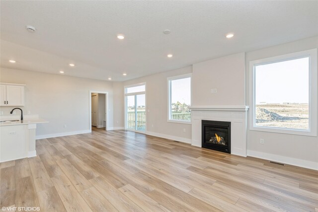 unfurnished living room with light hardwood / wood-style floors and sink