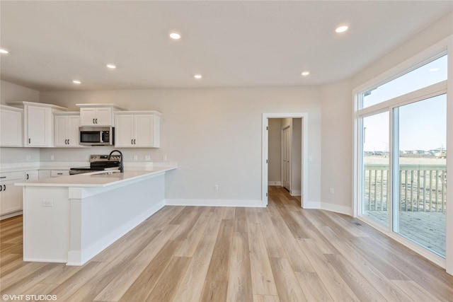 kitchen featuring white cabinets, appliances with stainless steel finishes, light hardwood / wood-style floors, and sink