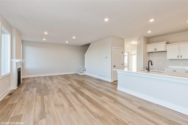 unfurnished living room featuring light hardwood / wood-style floors and sink